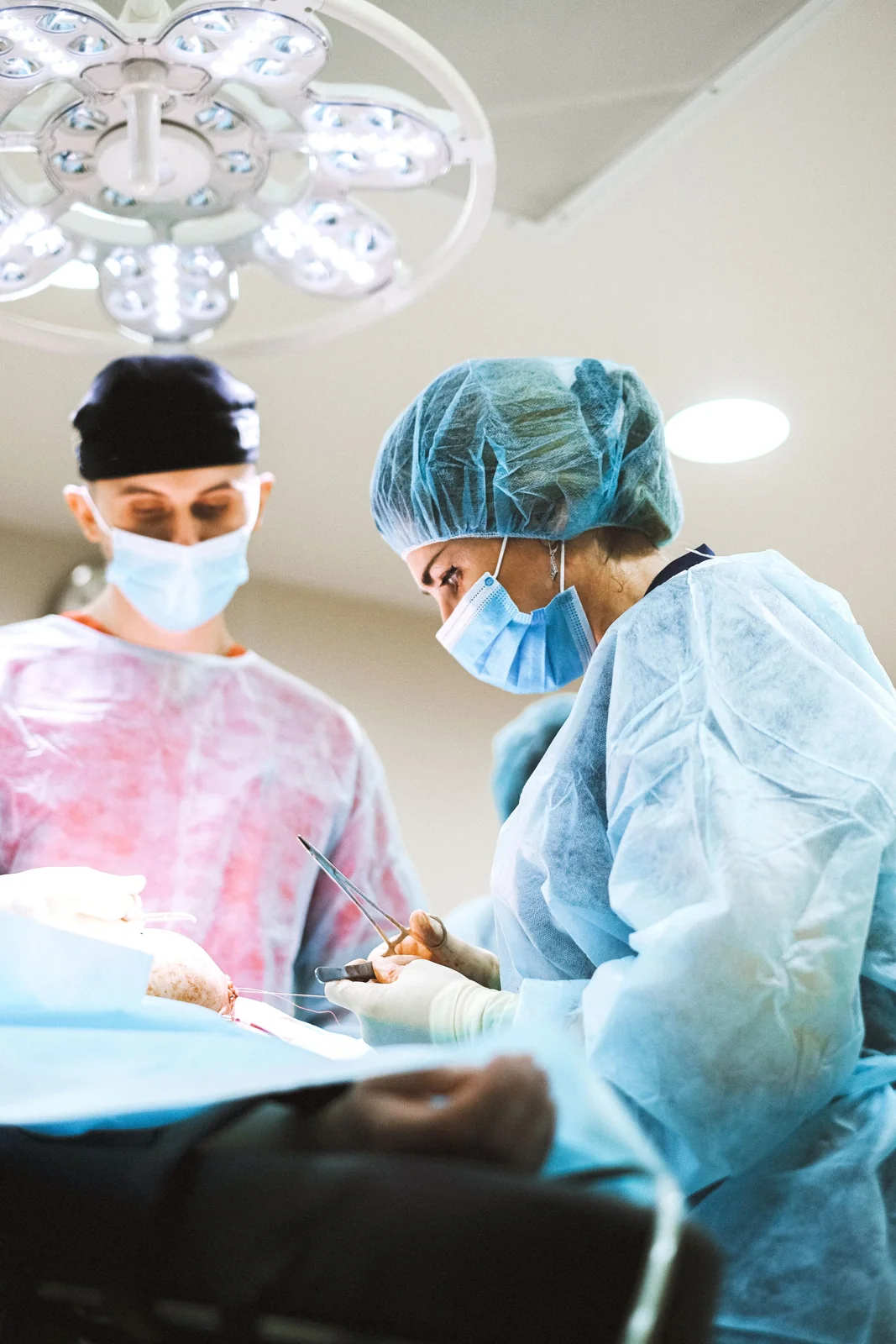 Two surgeons working together under surgical lights; illustrative clinical photography